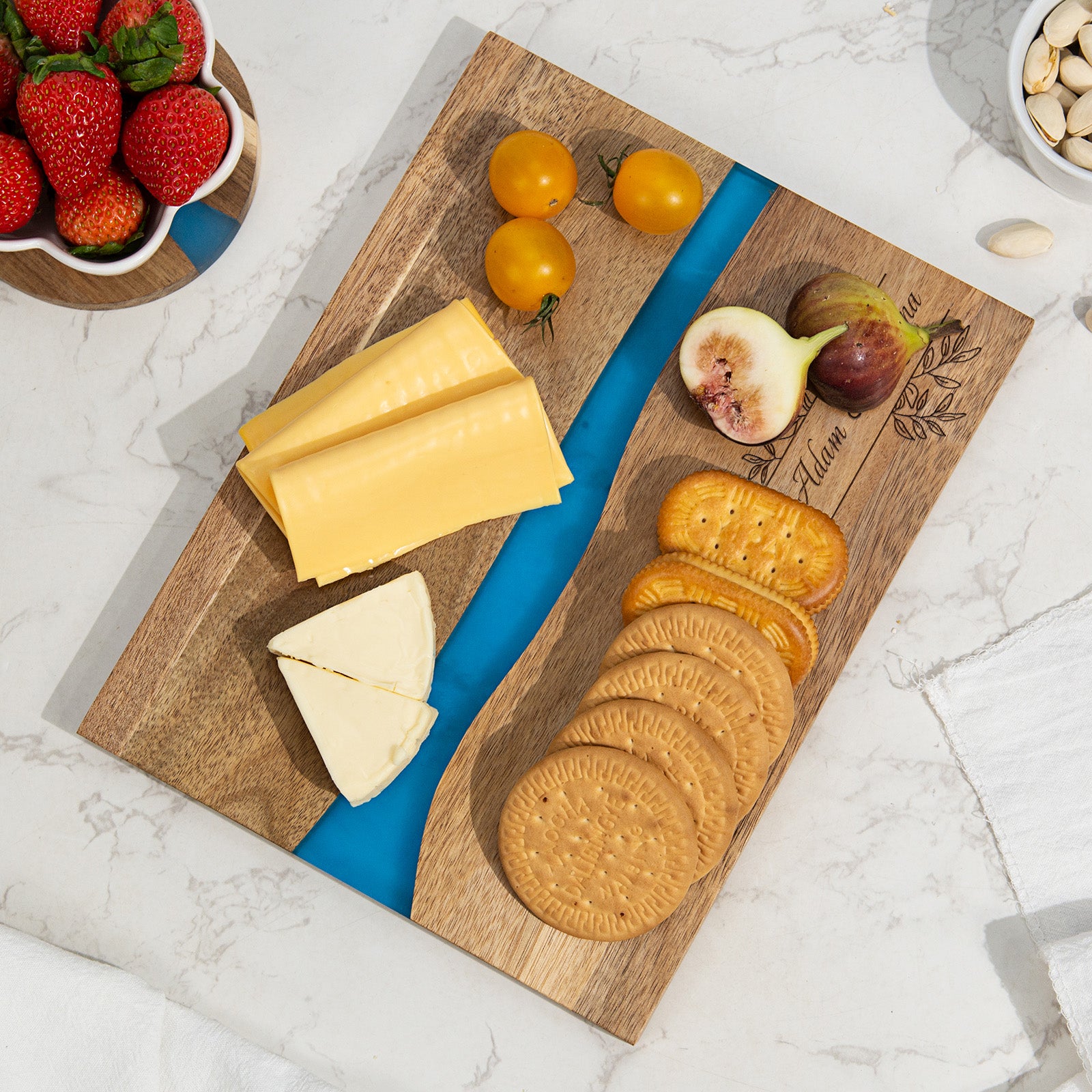 Personalized epoxy resin cutting board with couples names laser engraved on acacia wood with blue river resin inlay